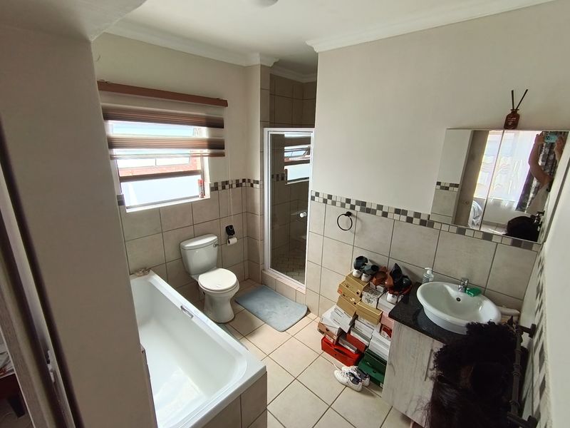A functional bathroom featuring a bathtub, separate shower enclosure, vanity with basin, and neutral wall and floor tiling.