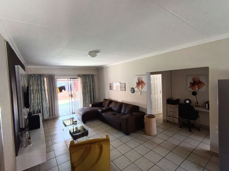 A spacious living area featuring tiled flooring, a built-in desk nook, and a sliding glass door providing access to the outdoor space.