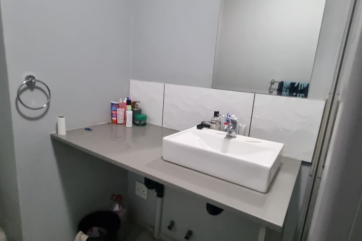A functional bathroom featuring a modern vessel sink, chrome faucet, and a wall-mounted mirror with a tiled splashback.