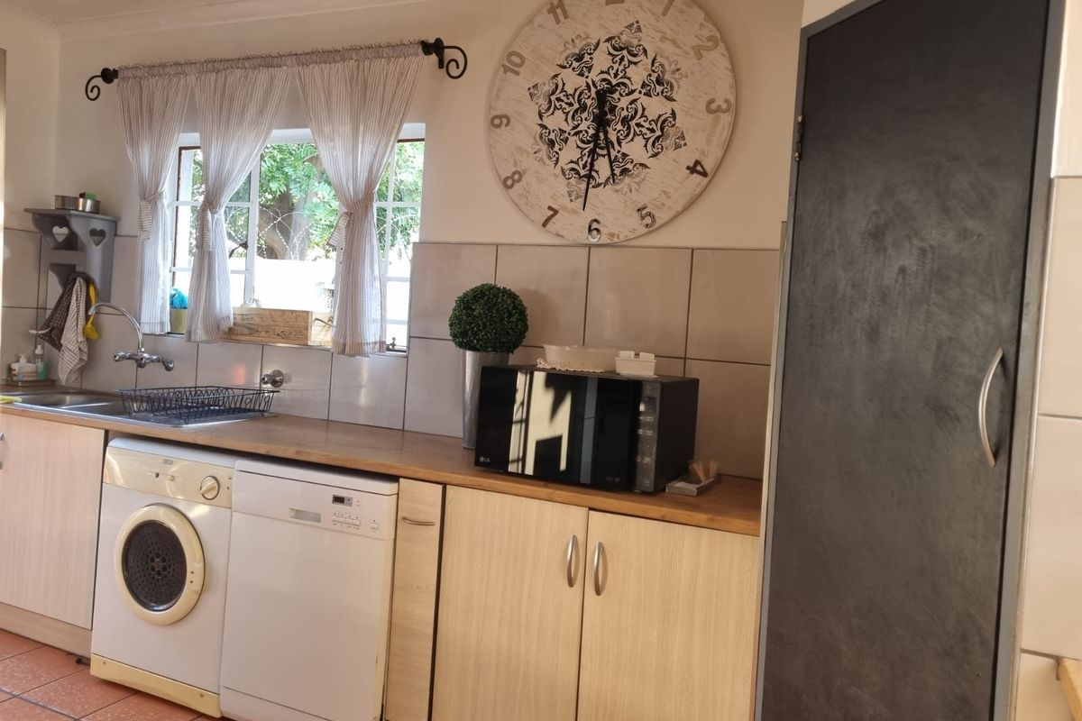 A functional kitchen area featuring laminate countertops, built-in cabinetry, a stainless steel sink, and tiled backsplash with integrated appliance spaces.