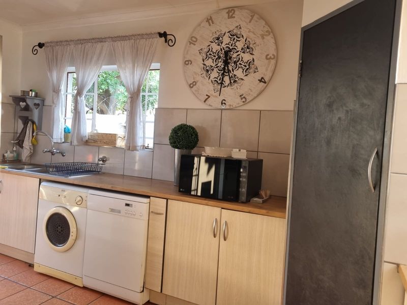 A functional kitchen area featuring laminate countertops, built-in cabinetry, a stainless steel sink, and tiled backsplash with integrated appliance spaces.
