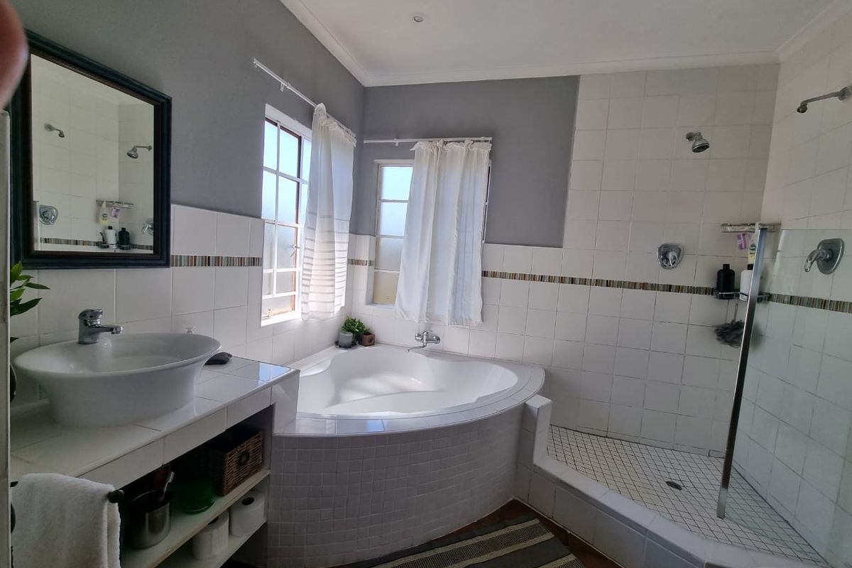 A functional bathroom featuring a corner bathtub, a separate walk-in shower, and a tiled vanity with a vessel sink.
