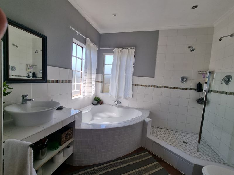 A functional bathroom featuring a corner bathtub, a separate walk-in shower, and a tiled vanity with a vessel sink.