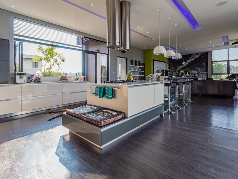 Modern open-plan kitchen featuring a central island with gas hob, sleek cabinetry, recessed lighting, and large bi-fold doors opening to the exterior.