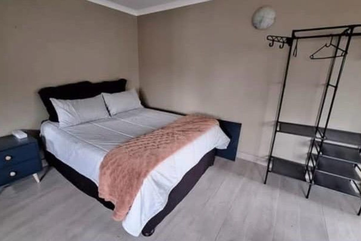 A bedroom featuring light-toned laminate flooring and neutral wall finishes, providing a functional and simple living space.