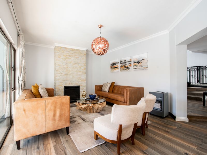 A bright and inviting living room featuring a stone-clad fireplace, modern laminate flooring, and large sliding glass doors providing ample natural light.