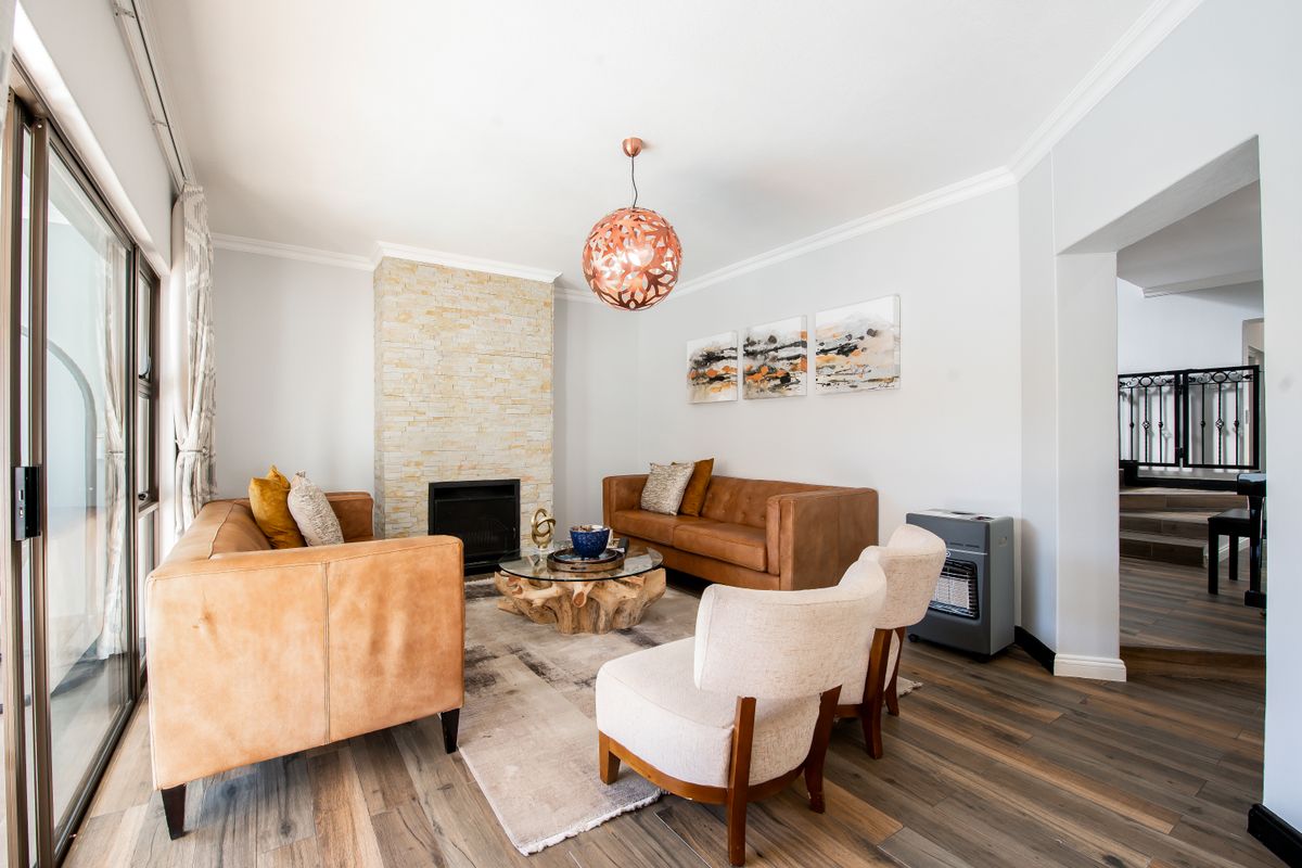 A bright and inviting living room featuring a stone-clad fireplace, modern laminate flooring, and large sliding glass doors providing ample natural light.