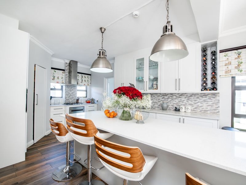 Modern kitchen featuring a large central island with quartz countertops, built-in appliances, stylish pendant lighting, and ample white cabinetry with integrated wine storage.