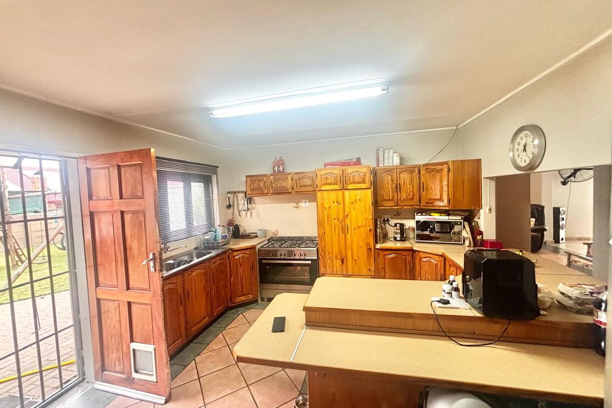A functional kitchen featuring wooden cabinetry, gas stove, built-in oven, and tiled flooring with direct access to the outdoor area.
