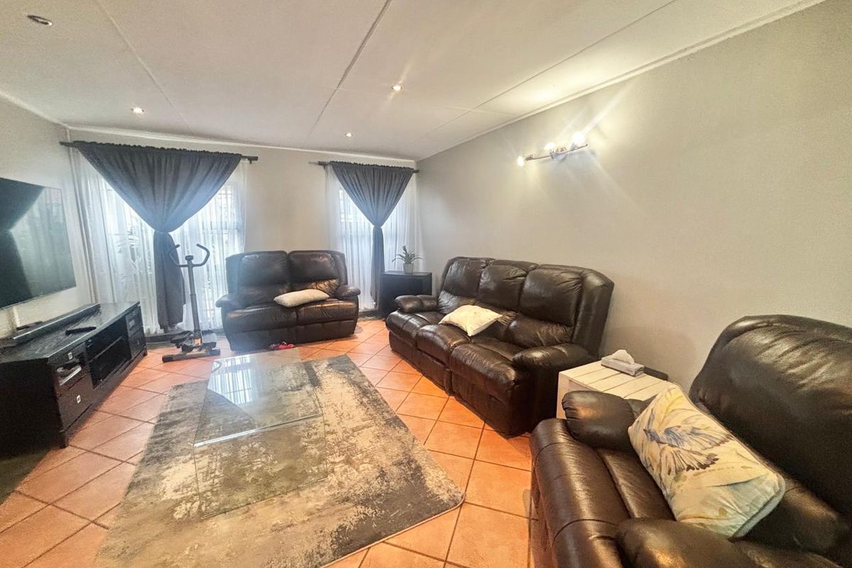 Spacious living room featuring terracotta floor tiles, recessed downlighting, and neutral wall finishes, providing a comfortable and functional family area.