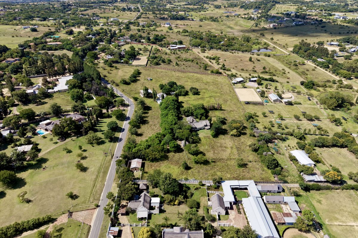 Aerial view of a large residential plot featuring established trees, open land, and existing outbuildings in a semi-rural setting.