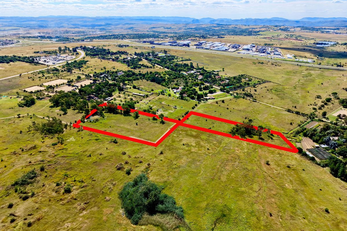 Aerial view of a large vacant residential land parcel with red boundary outlines, situated in a semi-rural landscape.