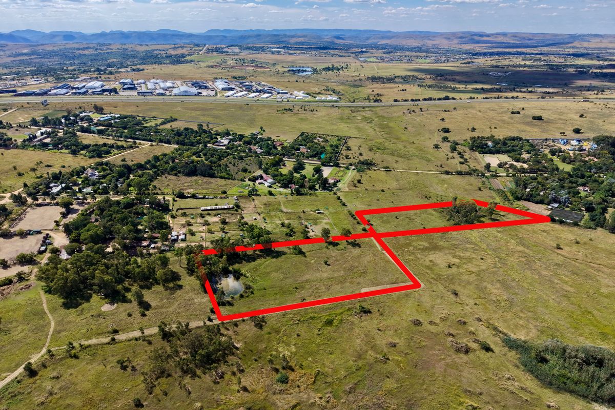 Aerial view of a large, undeveloped residential land parcel featuring open grassland and a natural pond, situated in a rural landscape.