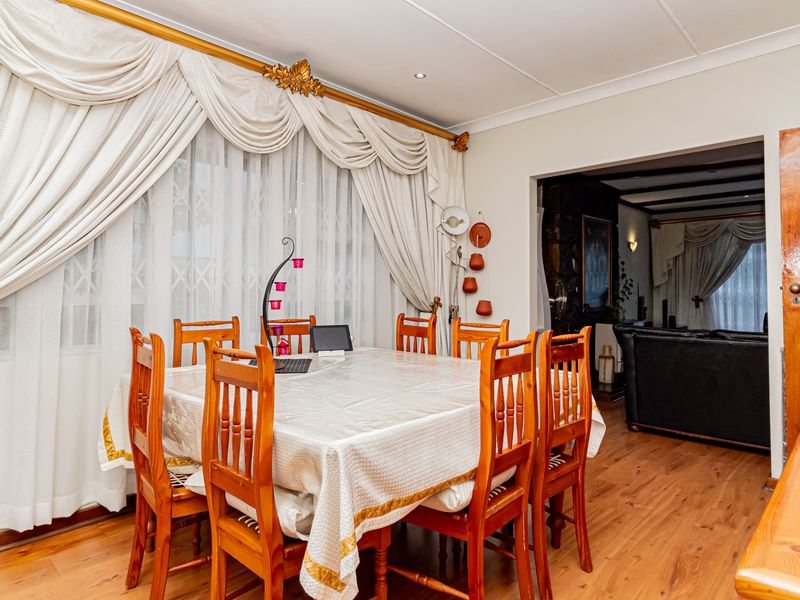 Dining room featuring timber flooring, recessed downlighting, and a louvered timber door, with an open-plan flow into the adjacent living area.