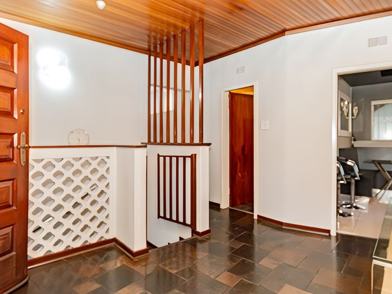 Entrance foyer featuring slate tile flooring, a timber panelled ceiling, and a decorative breeze block screen with a timber staircase balustrade.