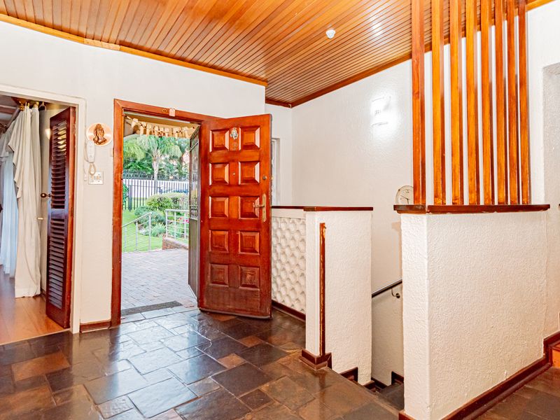 Spacious entrance hall featuring slate flooring, a timber-paneled ceiling, and a wooden staircase with a decorative screen divider.