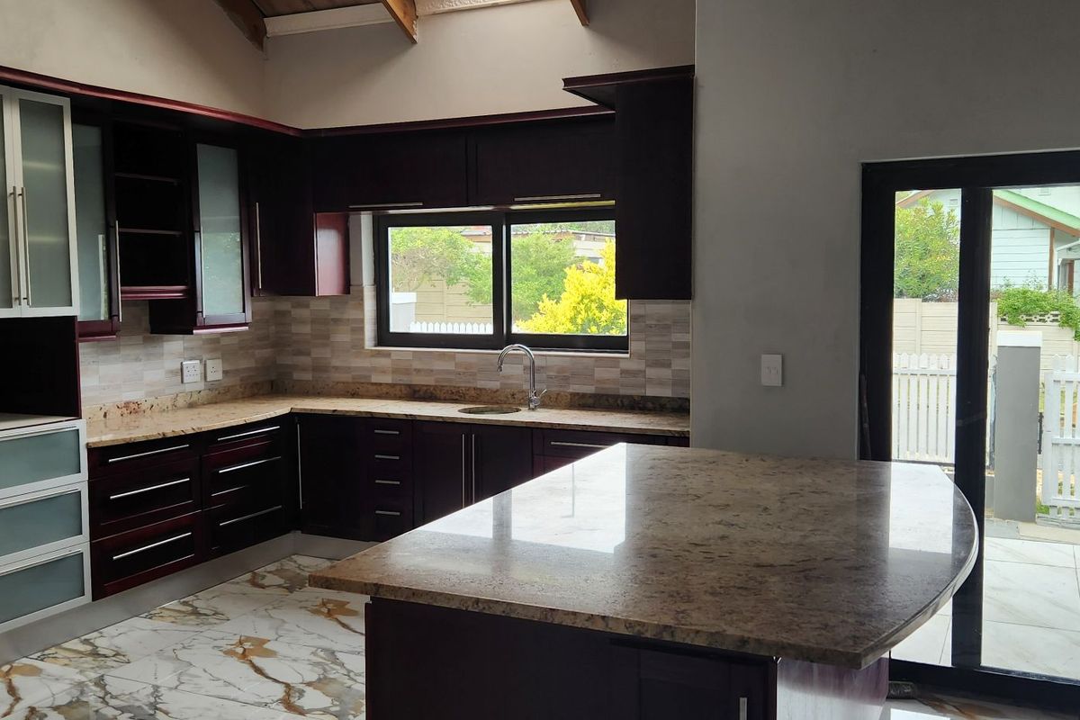 Modern kitchen featuring dark wood cabinetry, granite countertops, a central island, and sliding glass doors leading to the exterior.