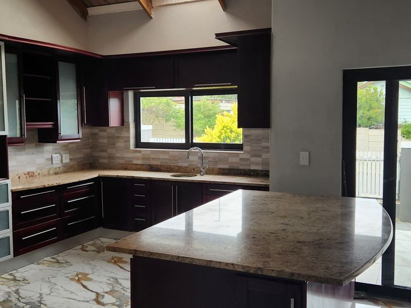 Modern kitchen featuring dark wood cabinetry, granite countertops, a central island, and sliding glass doors leading to the exterior.