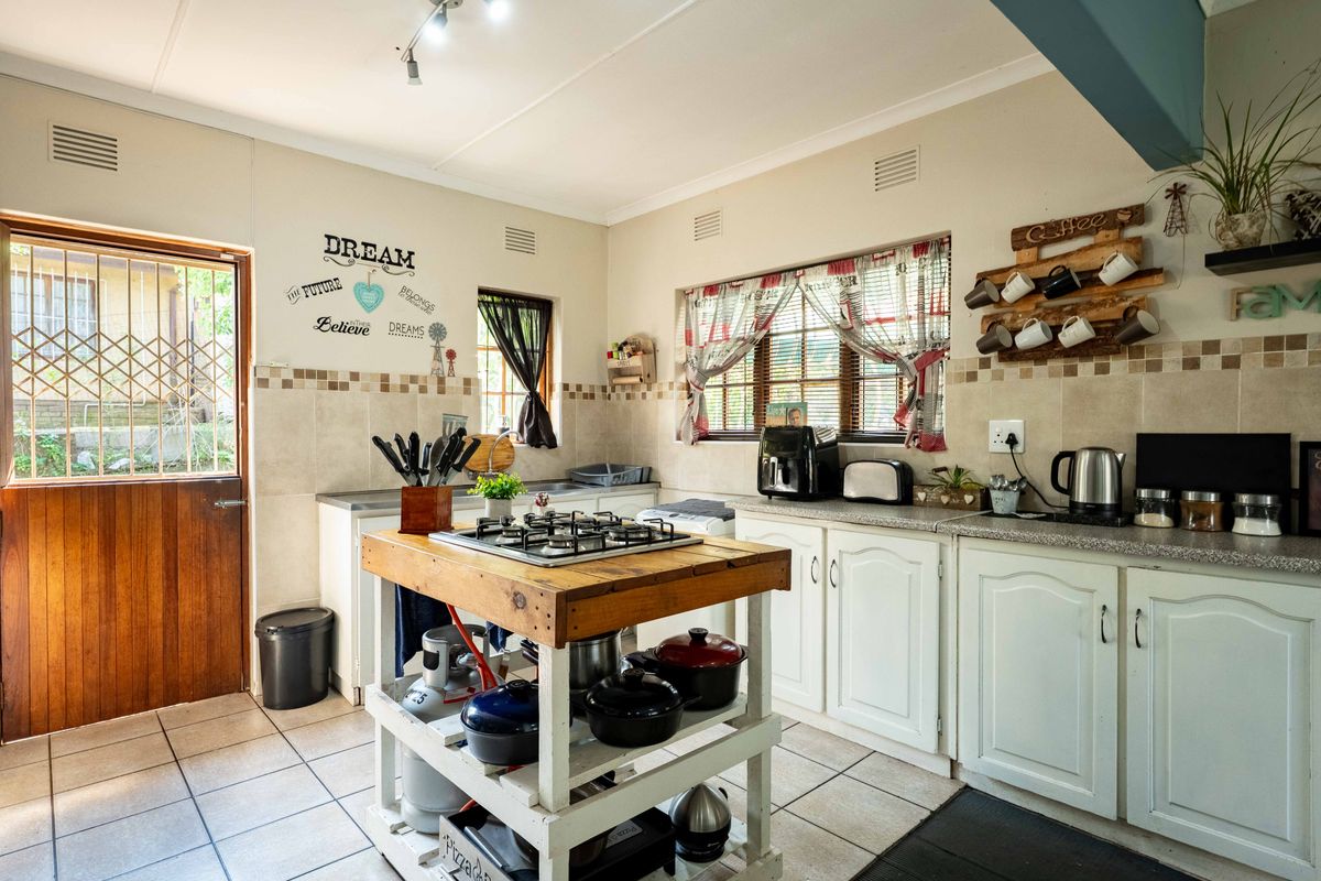 A functional kitchen featuring tiled flooring, built-in cabinetry, a tiled backsplash, and a central island with an integrated gas hob.