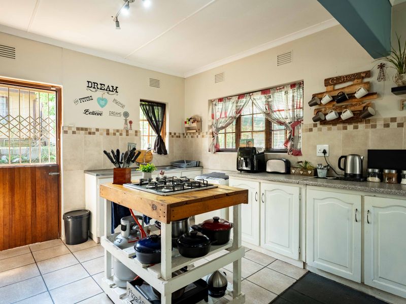 A functional kitchen featuring tiled flooring, built-in cabinetry, a tiled backsplash, and a central island with an integrated gas hob.