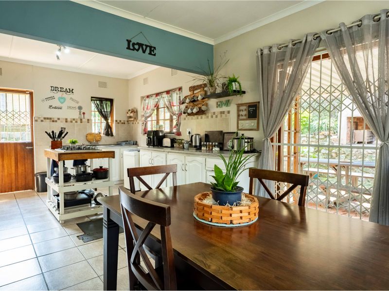Open-plan kitchen and dining area featuring tiled floors, built-in cabinetry, a gas hob, and direct access to the outdoor patio through a sliding door.