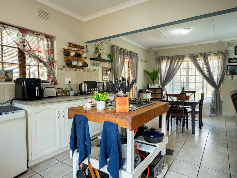 Open-plan kitchen and dining area featuring tiled flooring, built-in cabinetry, and a central wooden island with an integrated gas hob.