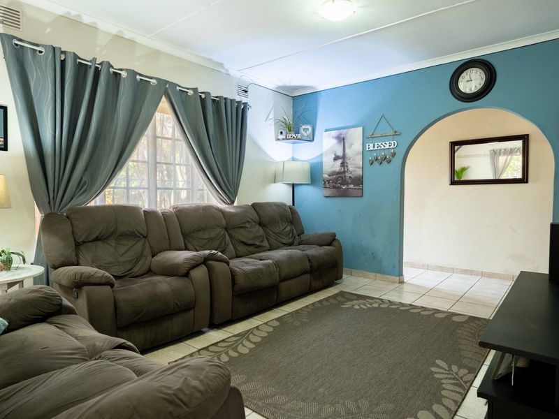 A comfortable living room featuring tiled flooring and a distinctive arched doorway leading to an adjacent space.