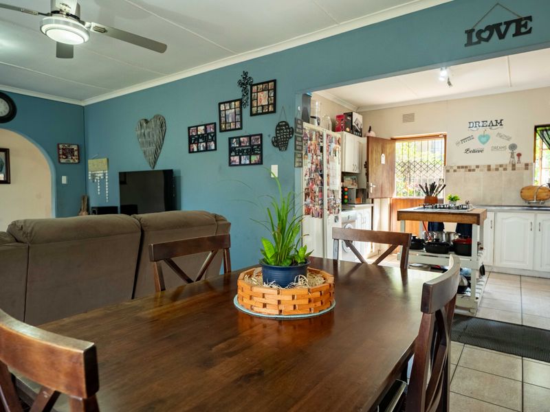 Open plan living and dining area flowing into a functional kitchen with tiled flooring and direct access to the exterior.