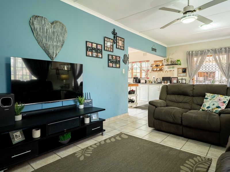 Open-plan living area featuring tiled flooring and a ceiling fan, with a direct view into the adjacent kitchen space.
