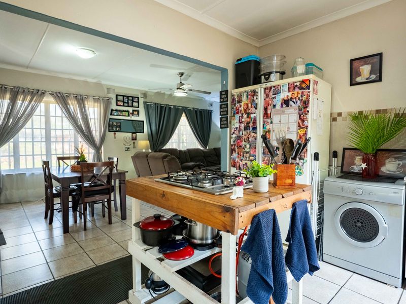 Open-plan kitchen and dining area featuring tiled flooring, a central gas hob island, and direct flow into the adjacent living space.