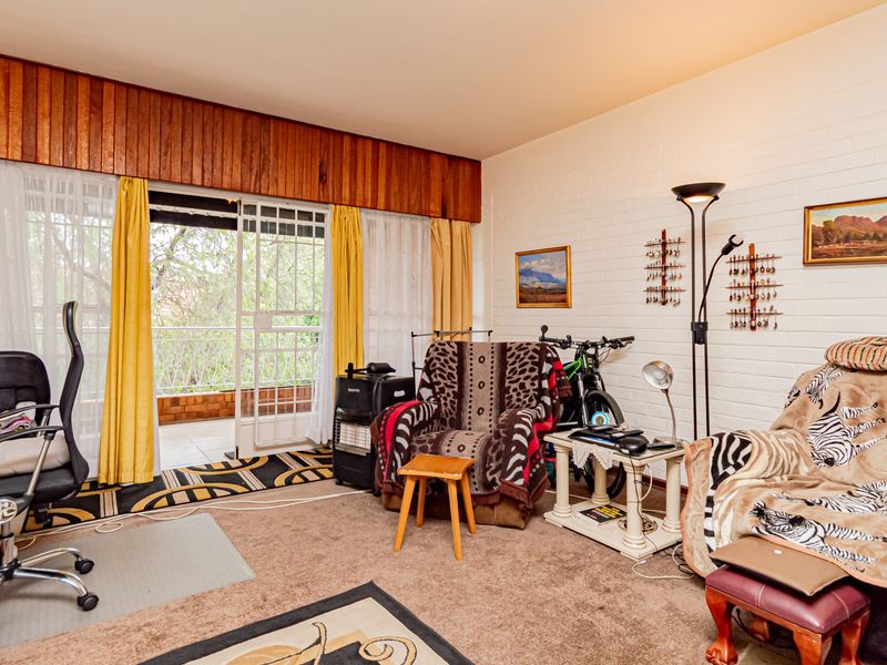 Living room featuring timber wall paneling, painted brick walls, and sliding glass door access to a private balcony.