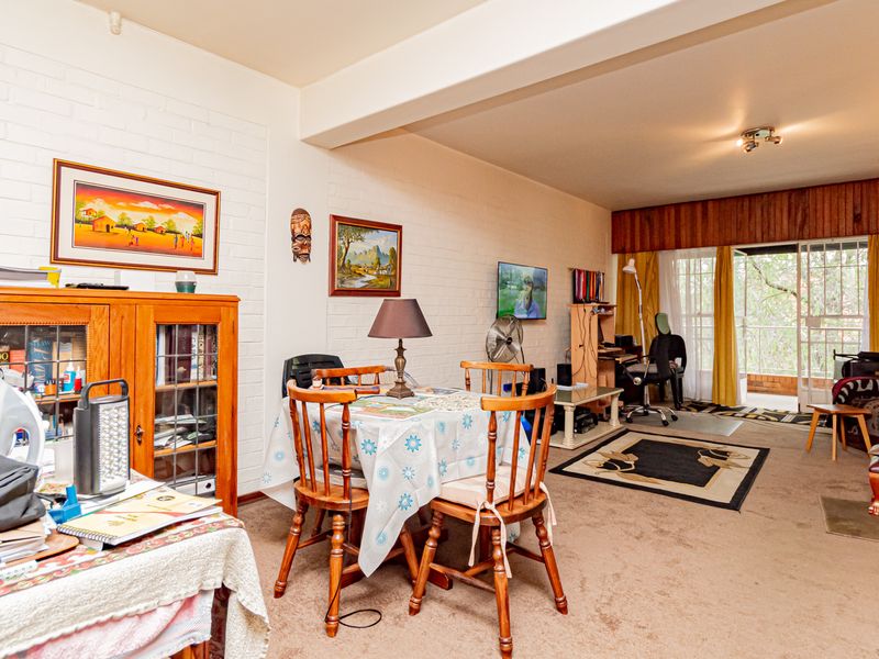 Open plan living and dining area featuring painted brick walls, carpeted flooring, and sliding glass doors leading to an outdoor space.