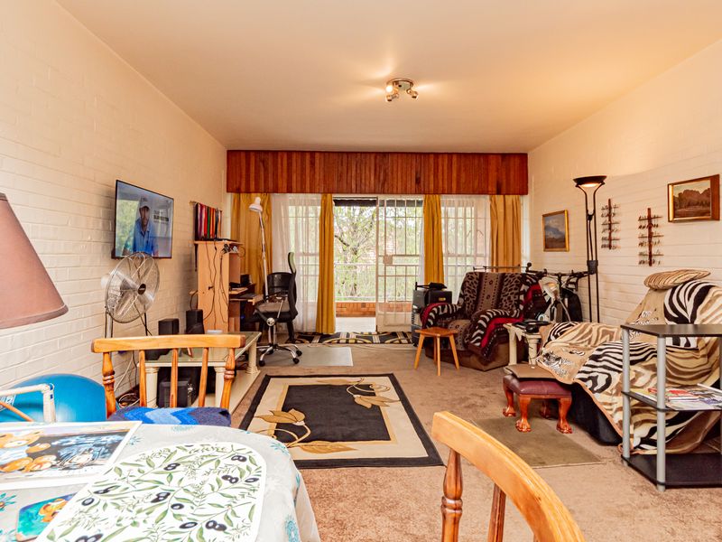 A living room featuring painted brick walls, carpeted flooring, and a sliding glass door leading to an outdoor area.