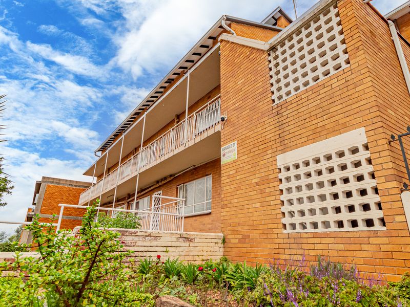 Exterior view of a multi-story apartment building featuring face brick construction, decorative breeze block screens, and balcony access.