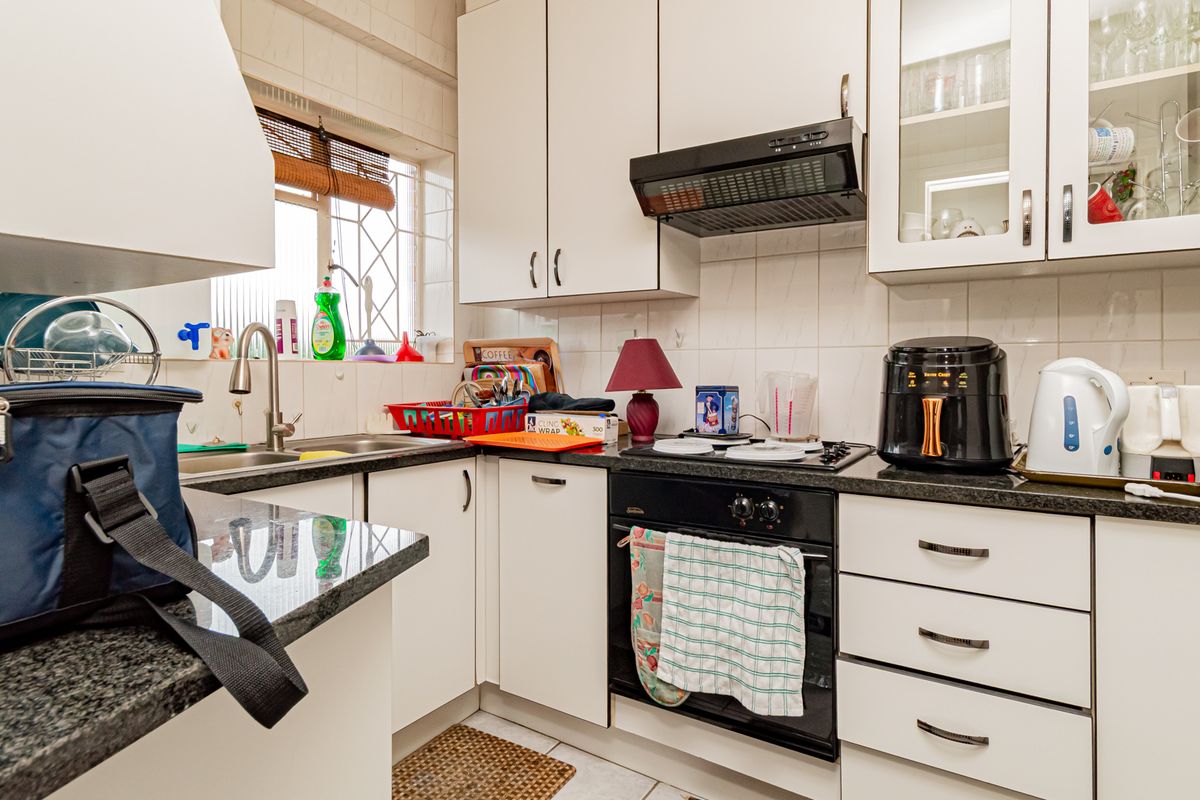 A functional kitchen featuring white cabinetry, granite countertops, a built-in oven with gas hob, and a tiled backsplash with a window for natural light.
