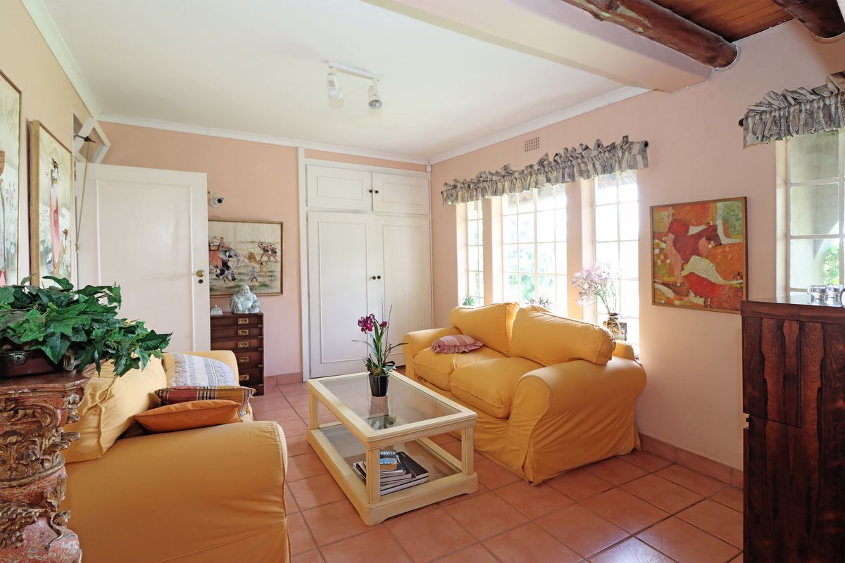 A cozy living room featuring terracotta floor tiles, exposed timber ceiling beams, and built-in storage cupboards, offering a warm and traditional aesthetic.