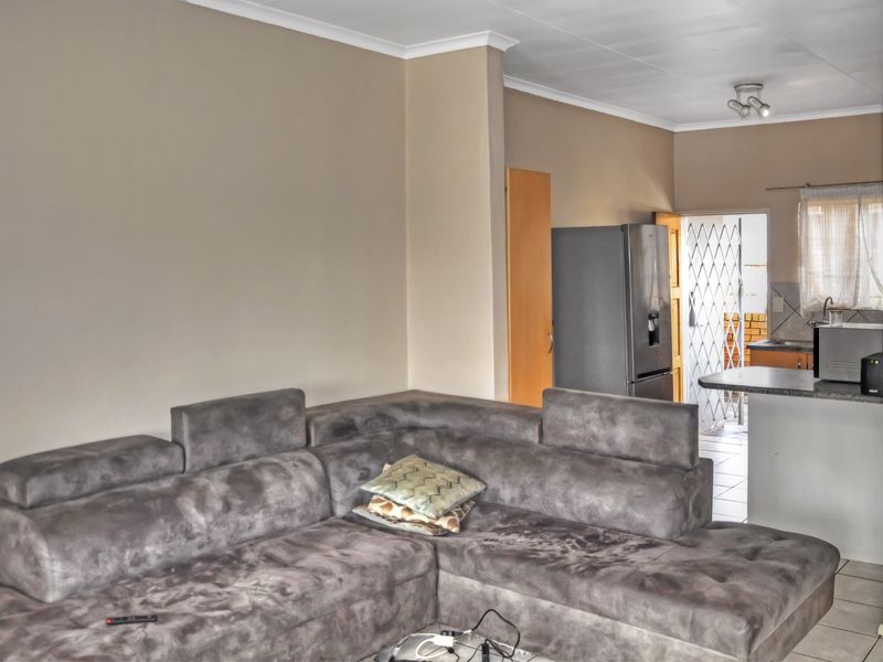 Open plan living area featuring tiled flooring, coved cornicing, and a breakfast bar connecting to the kitchen space.