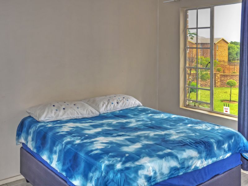 A bedroom featuring a grid-pane window with views of the surrounding complex grounds.
