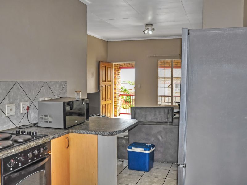 Open-plan kitchen and living area featuring tiled flooring, built-in cabinetry, and direct access to an outdoor balcony space.