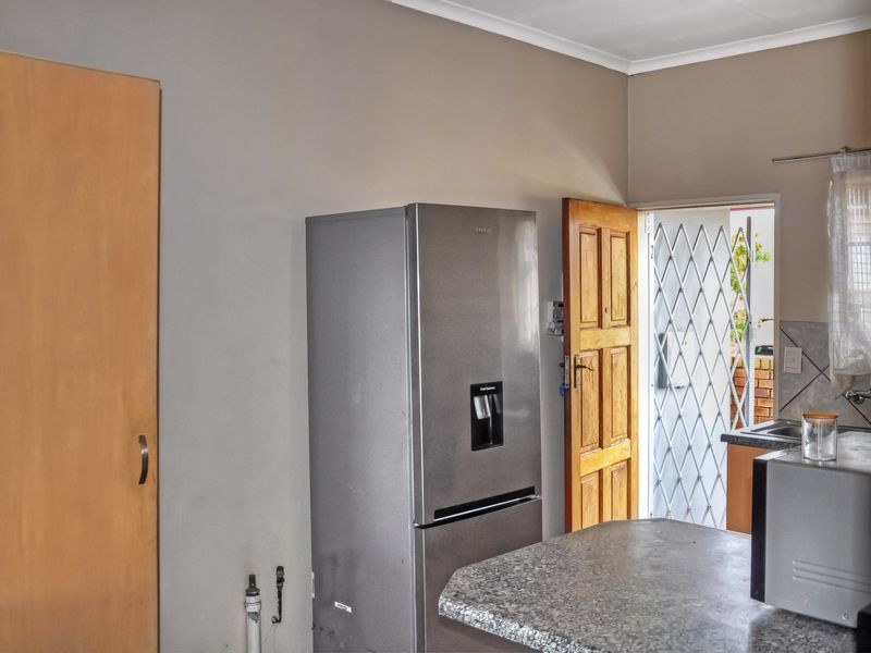 A functional kitchen area featuring granite countertops, built-in cabinetry, and direct access to an outdoor space through a secure timber door.