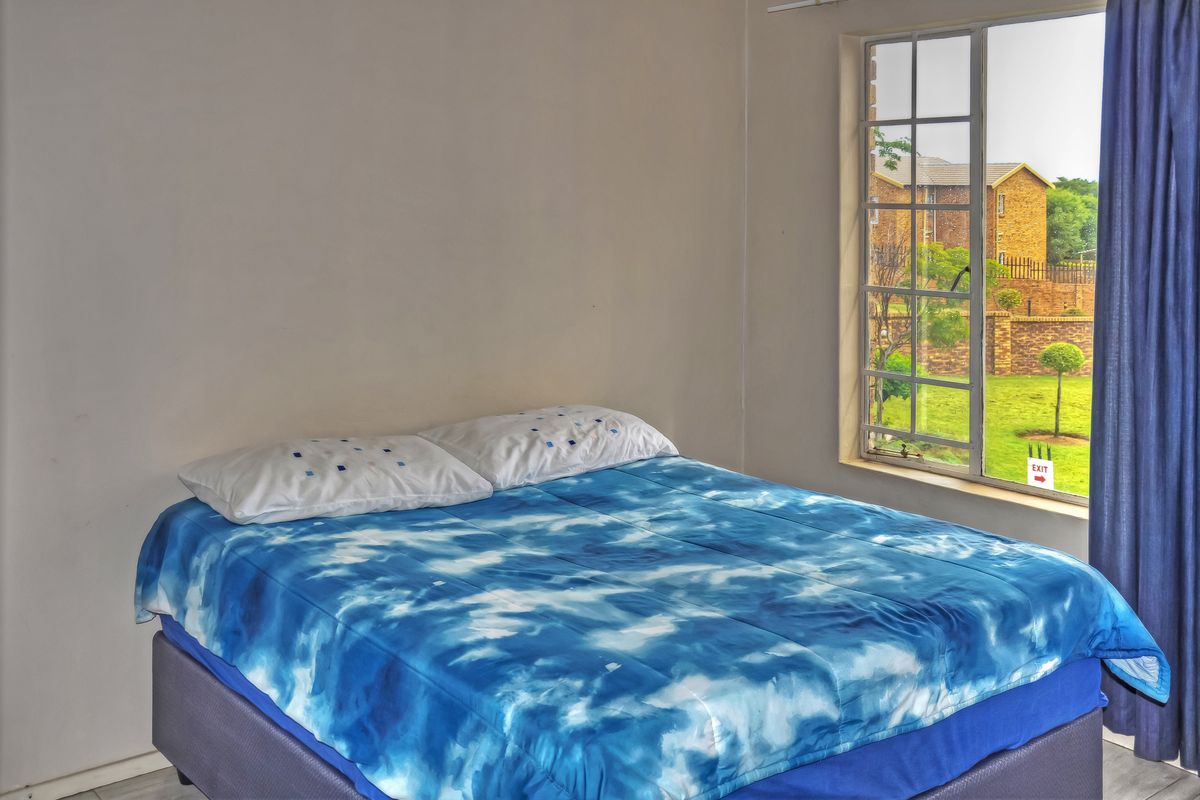 A bedroom featuring a grid-pane window with views of the surrounding complex grounds.