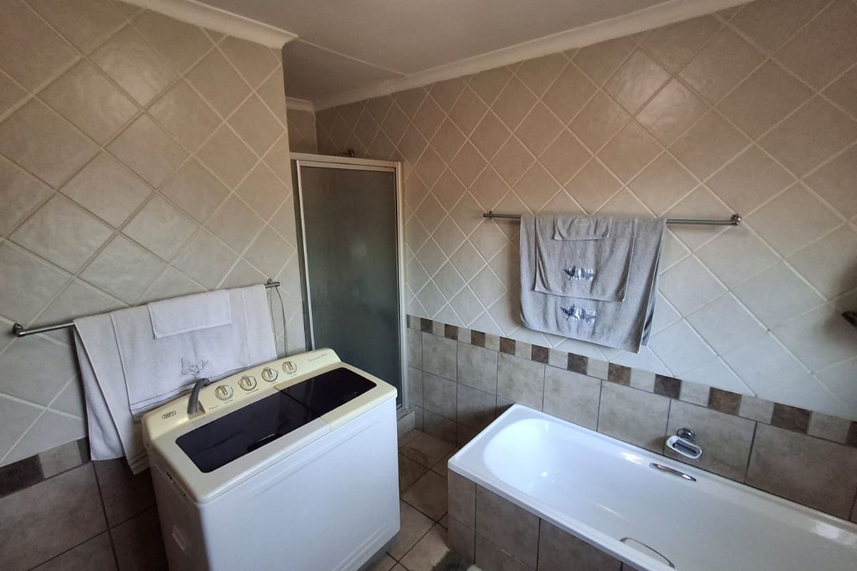 A functional bathroom featuring a built-in bathtub, a separate shower enclosure, and neutral wall and floor tiling.