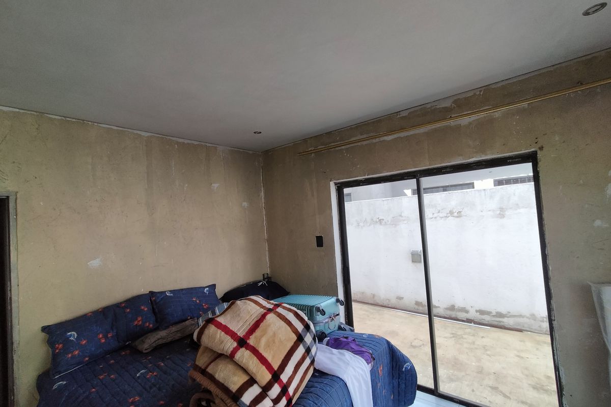 Bedroom featuring sliding glass doors leading to an outdoor area, currently requiring wall finishing and cosmetic updates to complete the space.