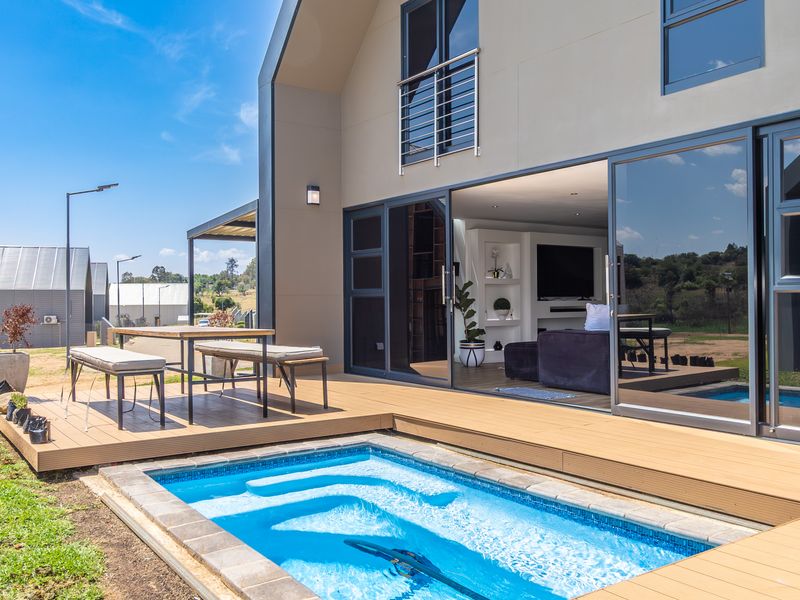 Modern rear exterior featuring a timber deck, a built-in swimming pool, and large sliding glass doors providing seamless indoor-outdoor flow to the living area.