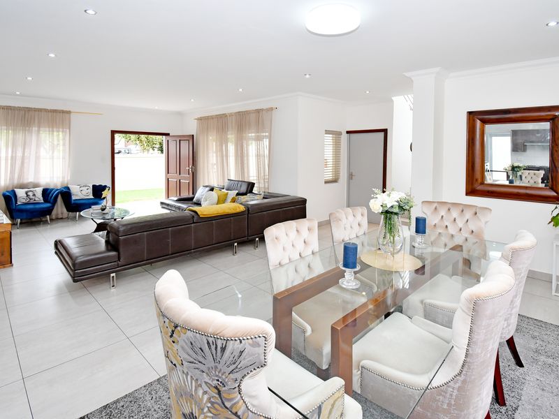 Spacious open-plan living and dining area featuring neutral tiled flooring, recessed lighting, and direct access to the outdoor space through a sliding glass door.