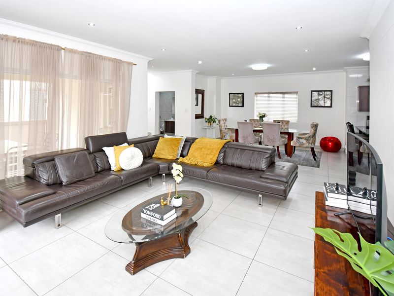 Spacious open-plan living and dining area featuring neutral tiled flooring, recessed lighting, and large sliding doors providing ample natural light.
