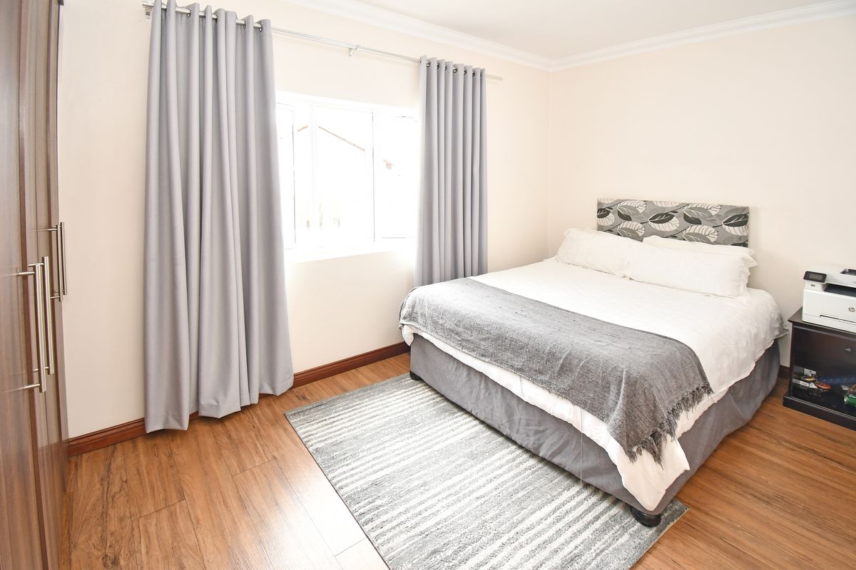 A well-maintained bedroom featuring laminate flooring, built-in wardrobe storage, and neutral wall finishes.