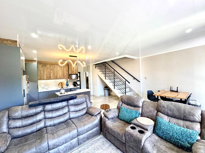 Spacious open-plan living area featuring a modern kitchen with island, integrated appliances, and a staircase leading to the upper level.
