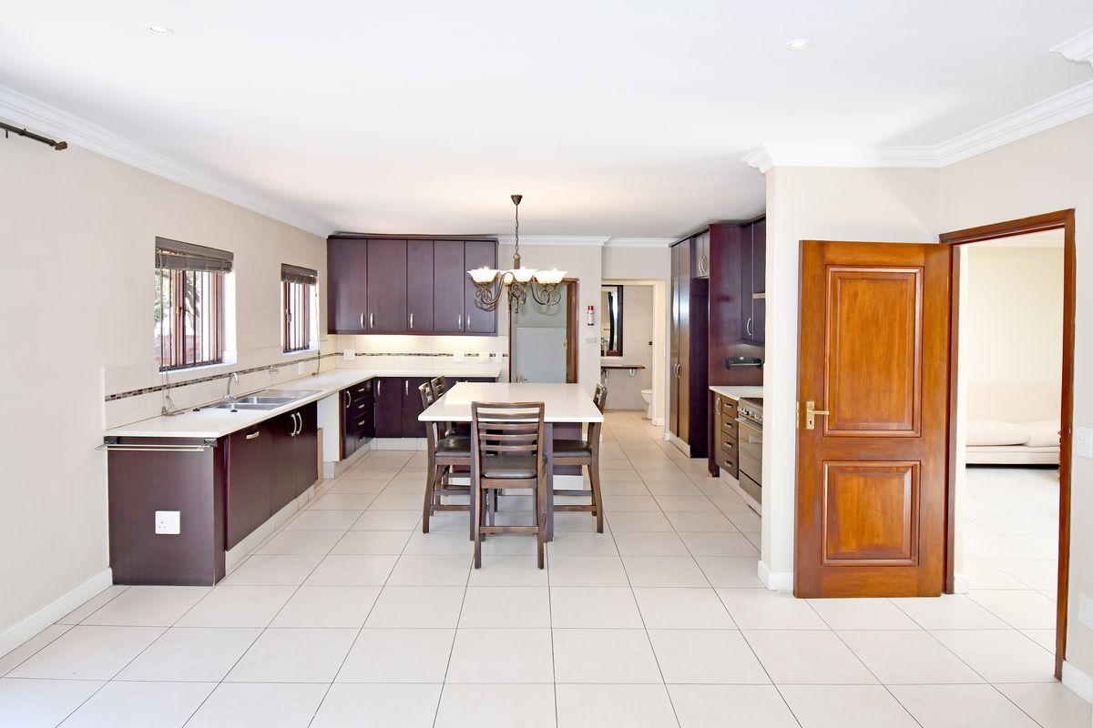 Spacious kitchen featuring dark wood cabinetry, stone countertops, a central island, and tiled flooring, offering a functional layout with ample storage space.