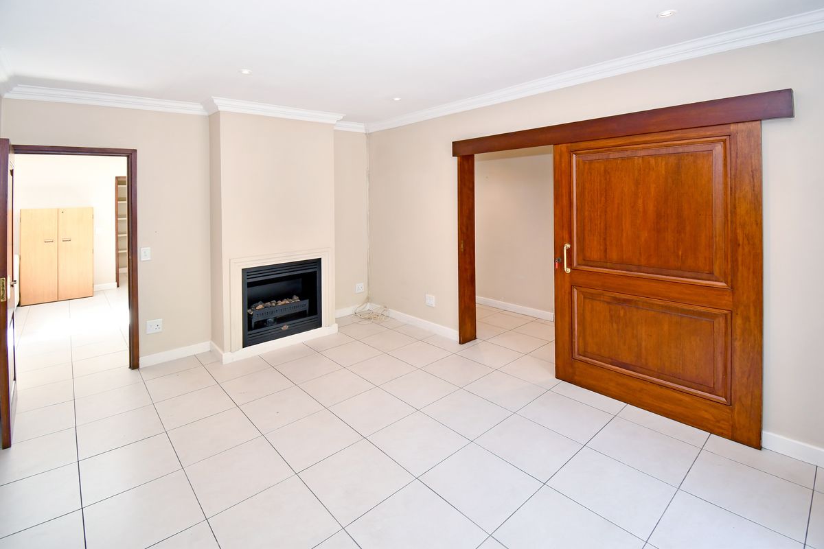 Spacious living area featuring neutral tiled flooring, a built-in fireplace, and a large wooden sliding door leading to an adjacent room.